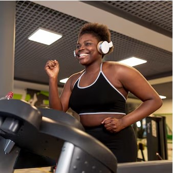 An African woman on a treadmill listening to music.